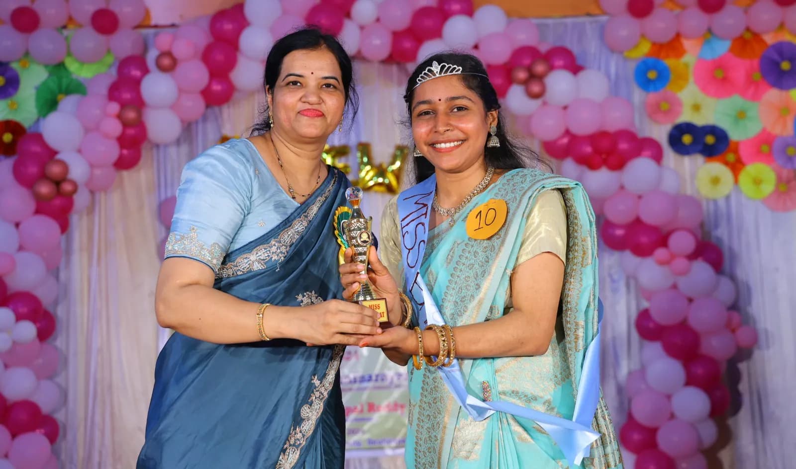 Student receiving recognition and a trophy on the college stage